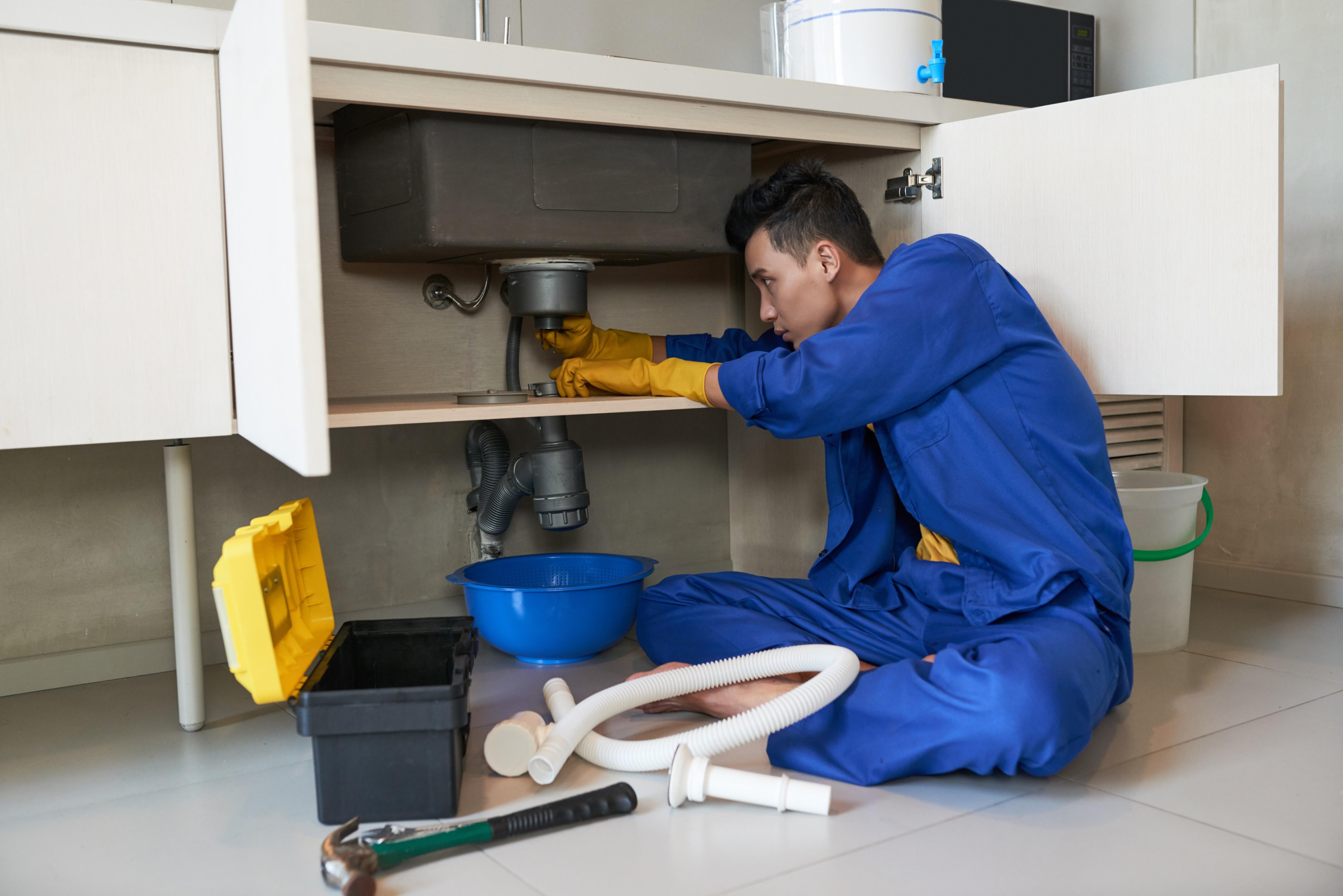 asian-plumber-blue-overalls-clearing-blockage-drain (1).jpg