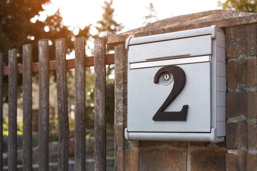 metal-mailbox-with-number-2-stone-fence-near-wooden-gate-outdoors-space-text_495423-48784.jpg